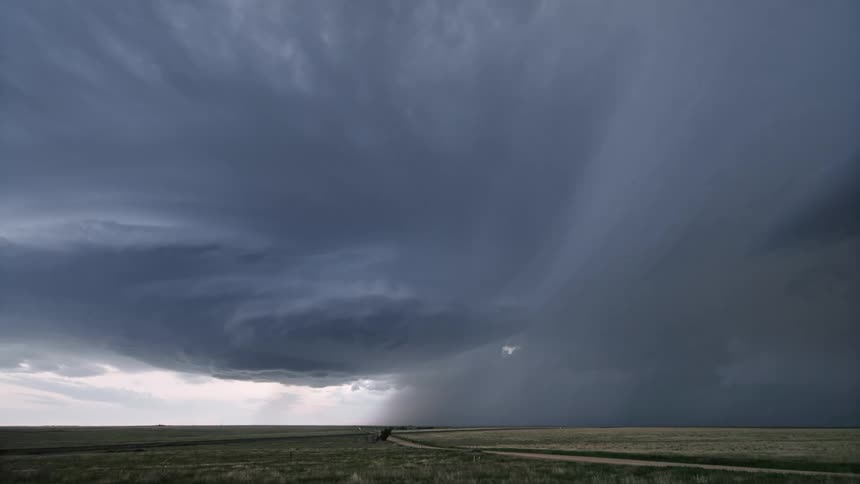 Extensive greenish field on a day with storm and lightning