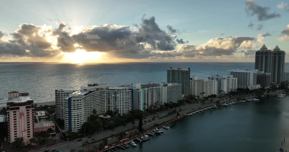Aerial panorama of a metropolis with large buildings by the sea and the sun on the horizon