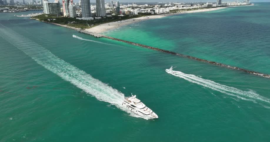 Coastal city skyline with highrise buildings against a clear blue sky a white yacht gliding through the water leaving a wake