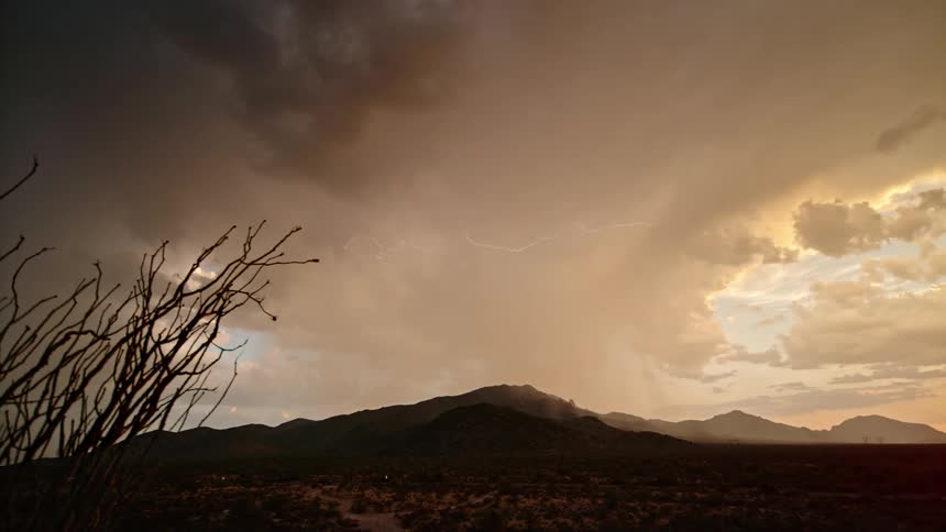Dark clouds produce lightning and rain over a mountain range