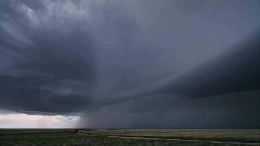 Cloudy sky with bright lightning above greenish fields