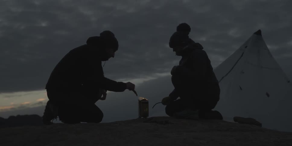 Two people light a small fire