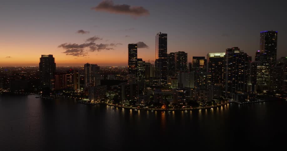 A large coastal city lit up as dusk falls