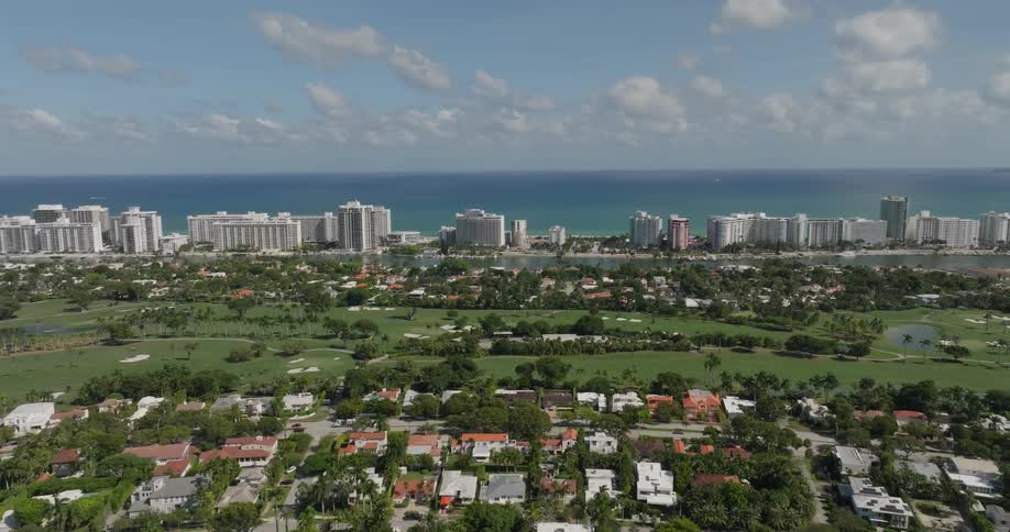 A coastal cityscape with a dense cluster of high rise buildings along the shoreline