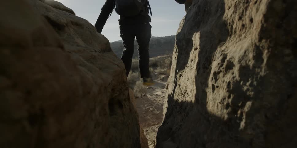 Hikers balance between two large boulders as they descend to the ground