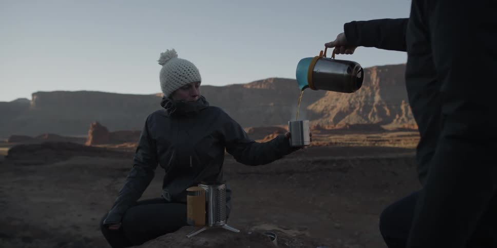 Two people are having some coffee at the top of a mountain