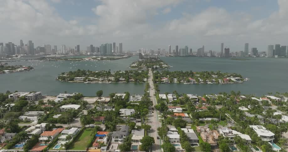 Aerial scene of residential neighborhoods on islands that cross the sea and with a metropolis on the horizon