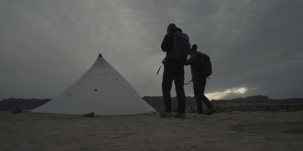 Two campers walk towards a white tent