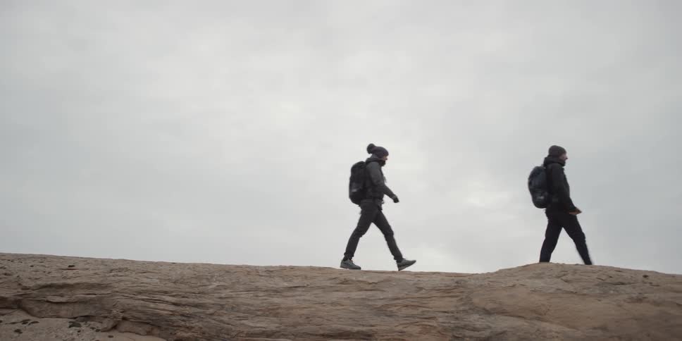 Two people hike on a cliff