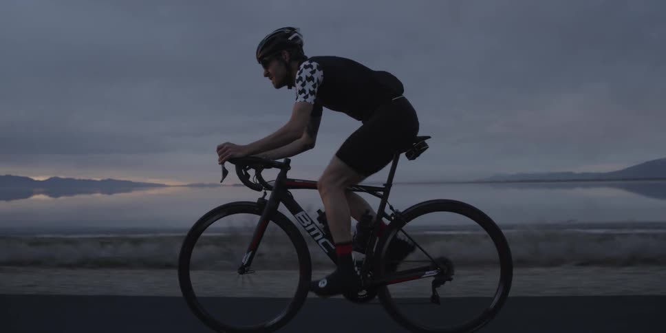 Man riding bicycle on highway near lake at dusk
