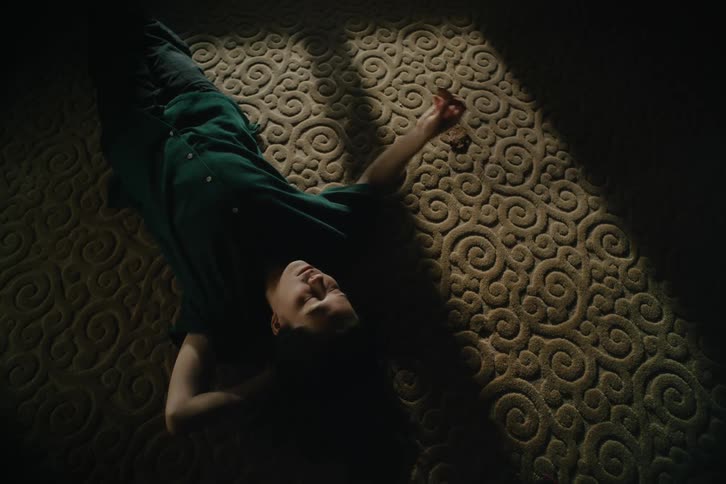 Person lying on a rug in a dark room eating a cookie