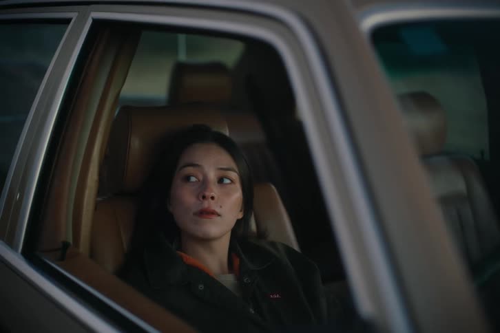 Woman sitting in the front seat of a parked car at night