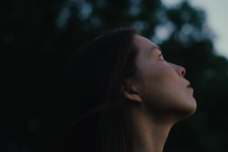 A woman with her eyes closed enjoying the wind in her face then opening her eyes and looking at the sky