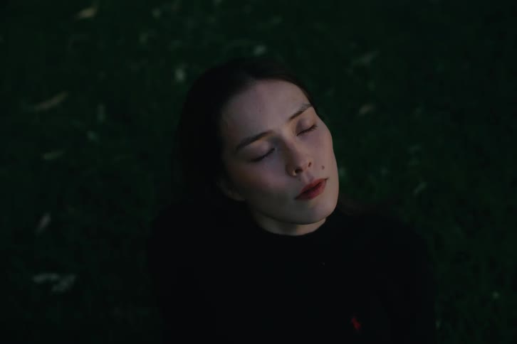 A face of a young woman who is looking up and closing her eyes