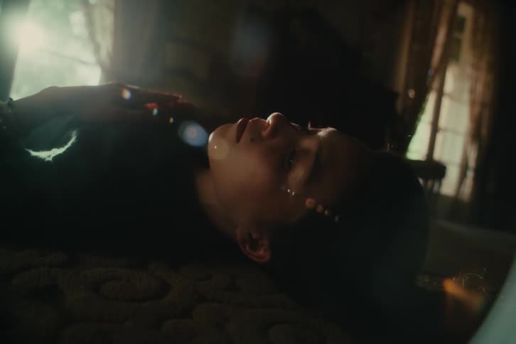 Woman lying on the floor in a shadowed room taps on her chest