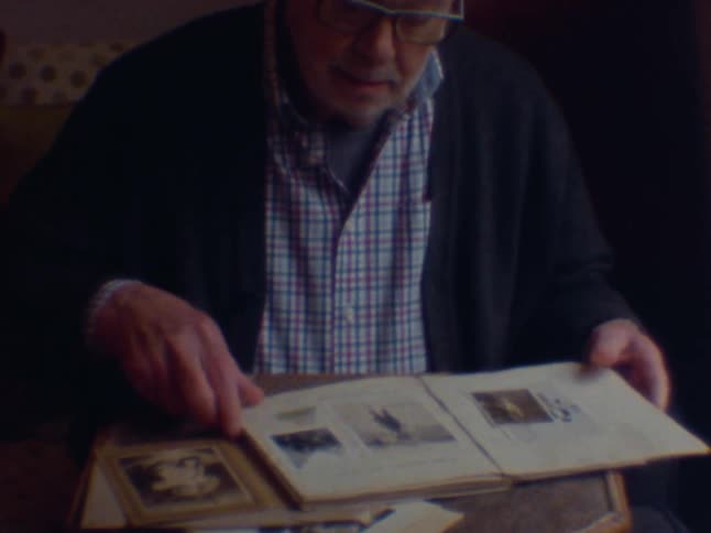 Elderly man sitting looking at a photo album