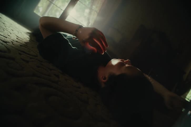A woman lies on a floor in a house and rubs her hands through her hair