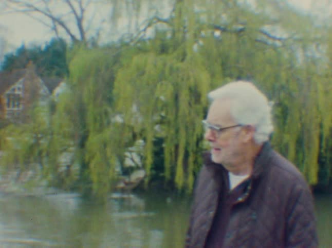 Smiling elderly man walking beside a lake