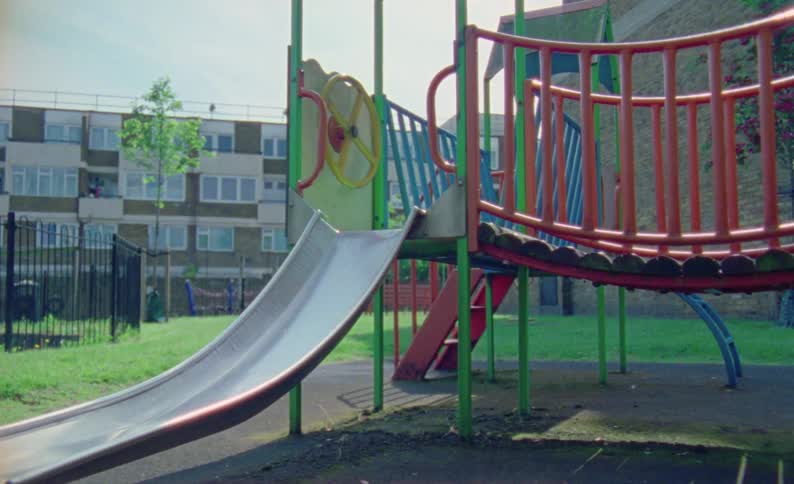 A colorful playground with a slide and climbing structures near residential buildings