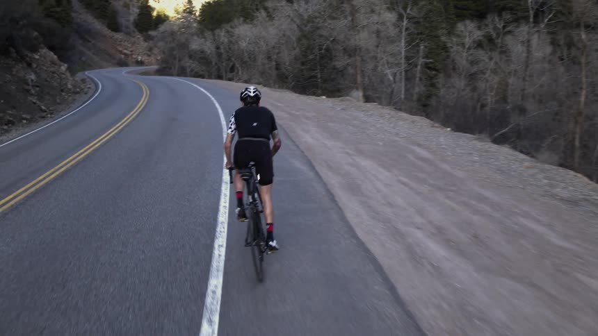 A person rides a bicycle on a mountain road