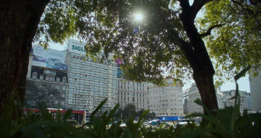 A sunny cityscape with tall buildings in the background and trees in the foreground