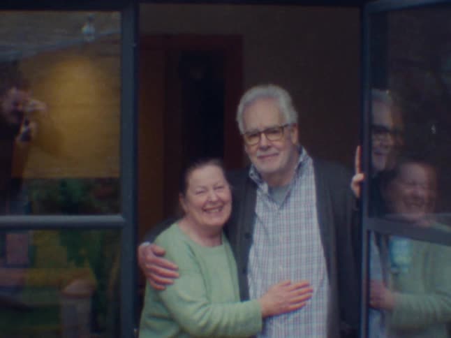 A couple stand in a doorway and smile and kiss
