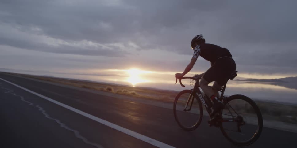 A person rides a bicycle on a highway at sunset
