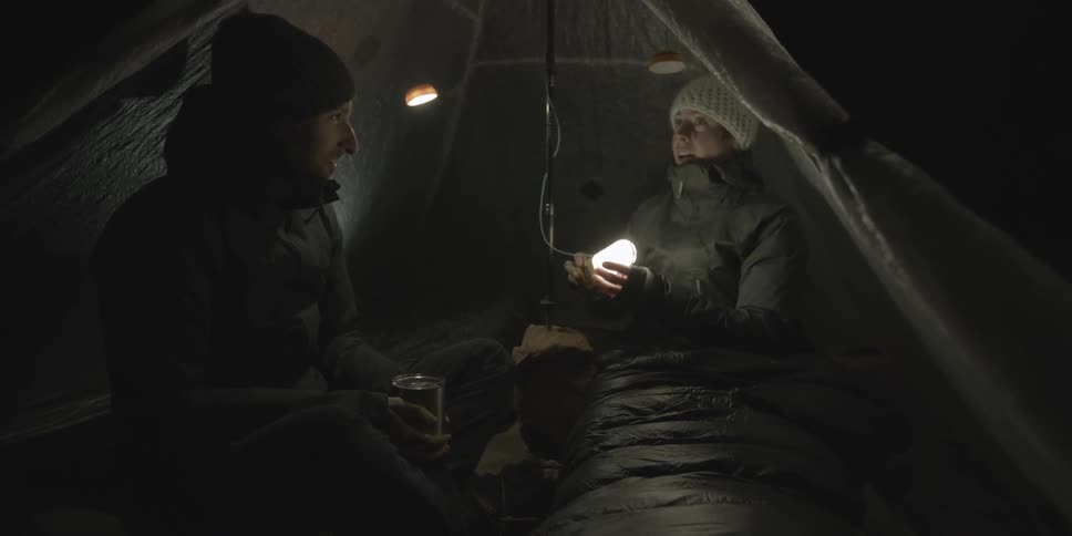 Woman working a light next to a man in a tent at night