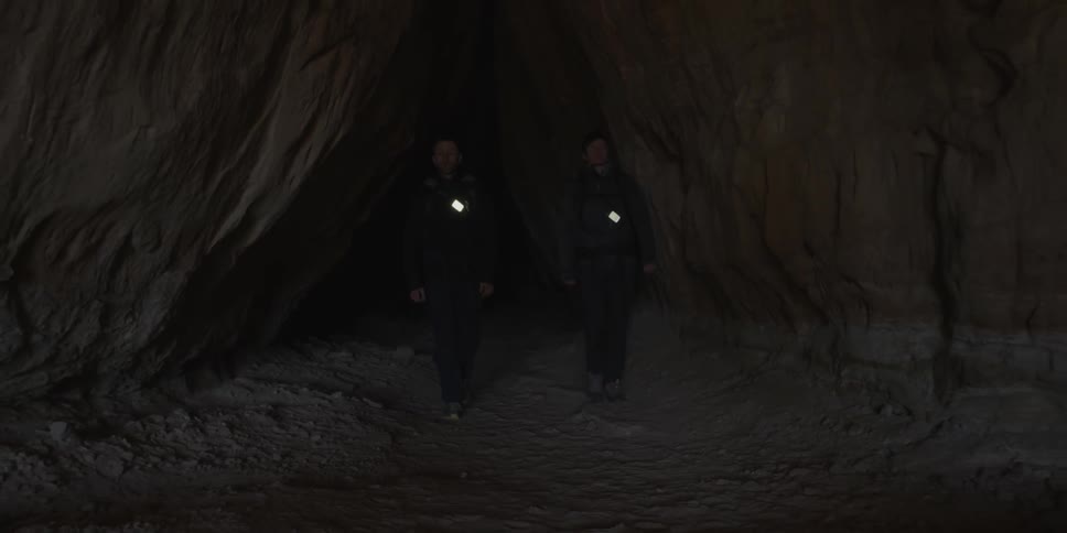 Two men emerge from a cave