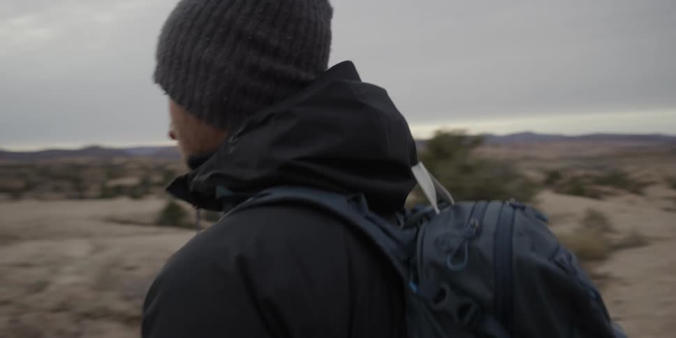 A man is walking in the desert wearing a backpack