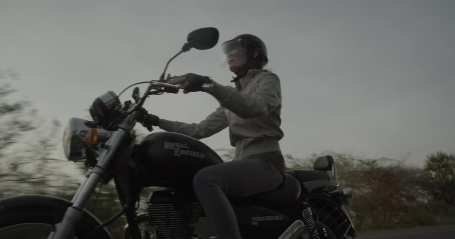 A woman riding a motorcycle at sunset
