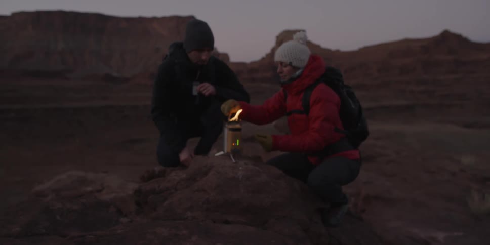 Man and woman using camp stove in wilderness at dusk