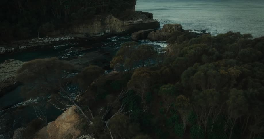 Aerial view of rock formations in the ocean with waves crashing against them