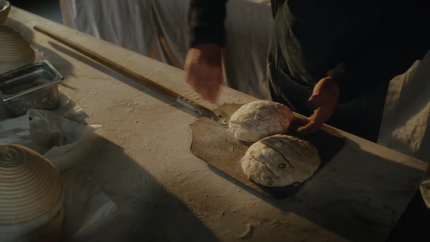 Hands kneading dough on a wooden surface in a rustic bakery
