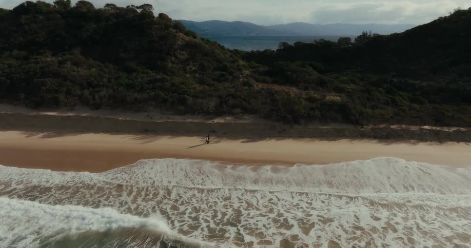 Two people walk on the beach together