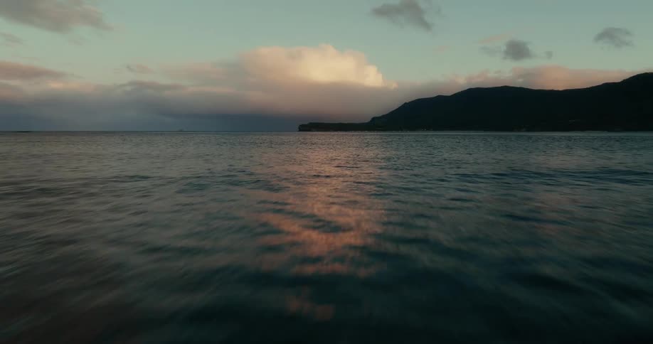 Aerial view of a serene seascape during twilight with distant mountains at dusk