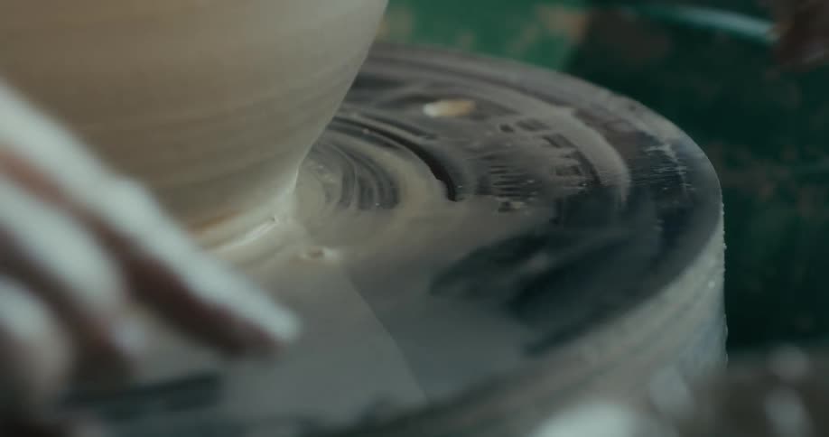 Preparation of a porcelain vase with a persons hand passing a thread