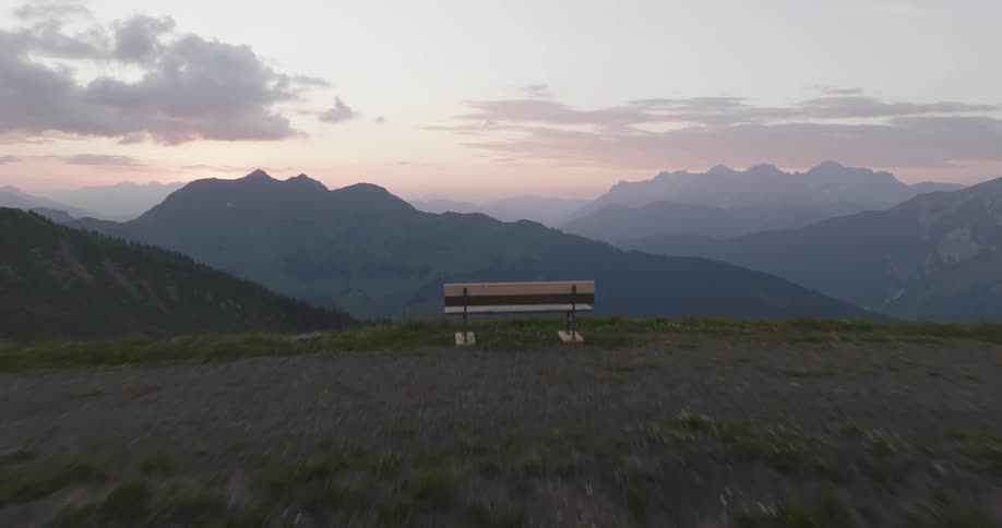 A lake with a bench in the distance and a serene mountain landscape