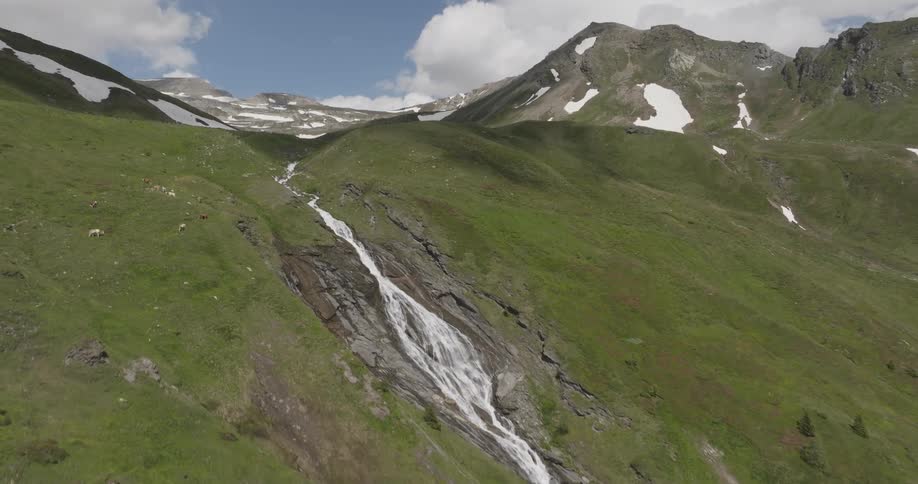 Greenish mountain with snow and a waterfall