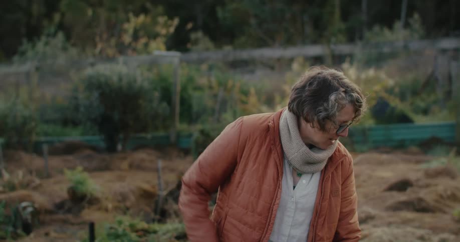Woman in an orange jacket working in a vegetable garden