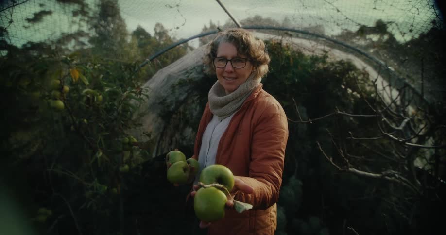 A woman is showing apples from the farm