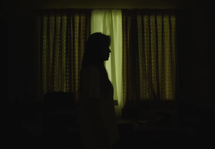 Silhouette of a woman walking in a room with low lighting