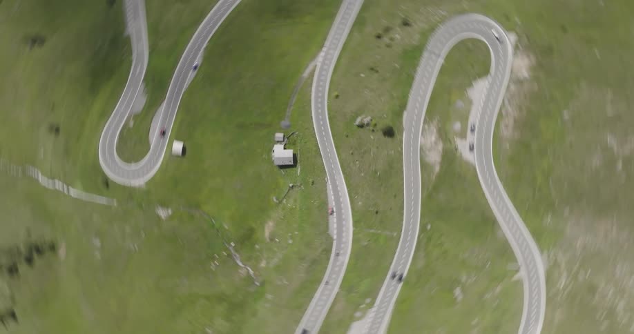 Spinning top view over a winding road surrounded by green flat land