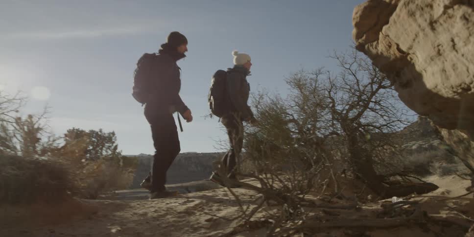 A man and woman hike through a valley