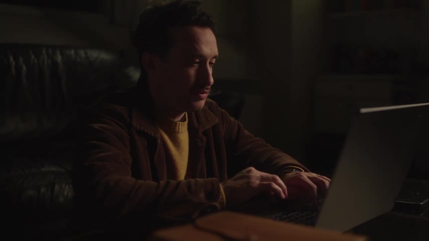 Man is sitting on a sofa typing on a laptop
