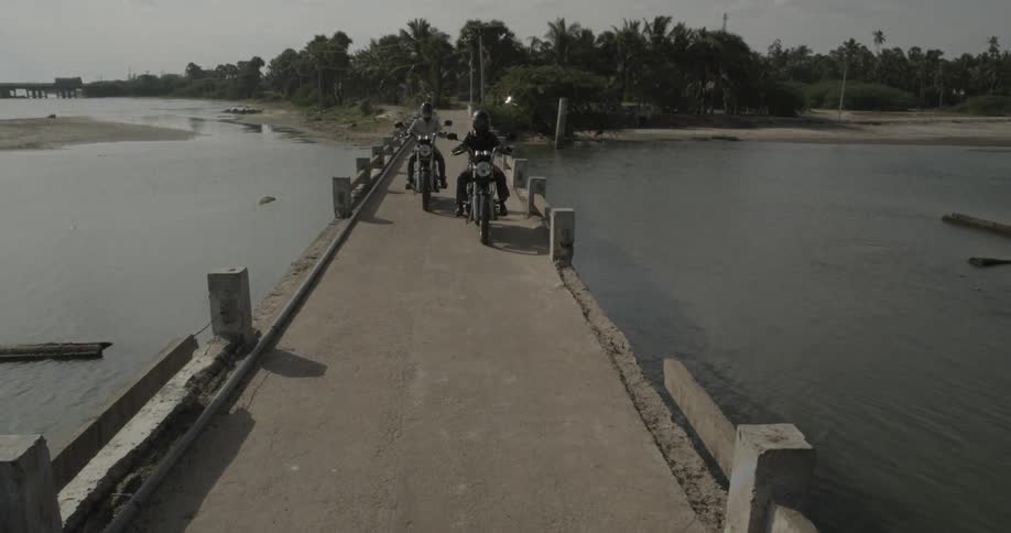 Two bikes drive down a stone bridge