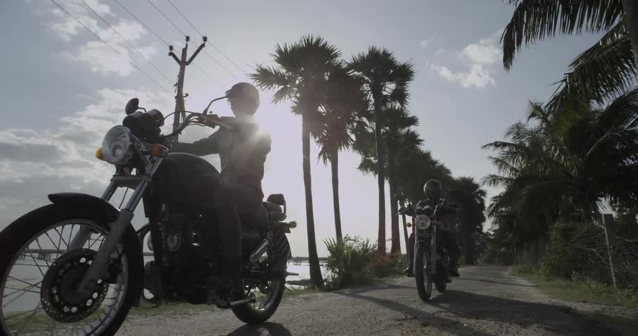 Two men on motorcycles driving down a small street