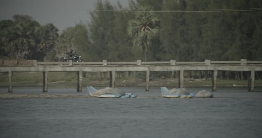 Motorcyclist crossing a bridge over a small river