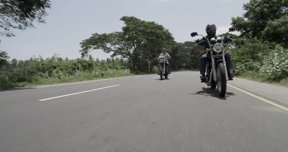 Two bikers are riding along an empty road