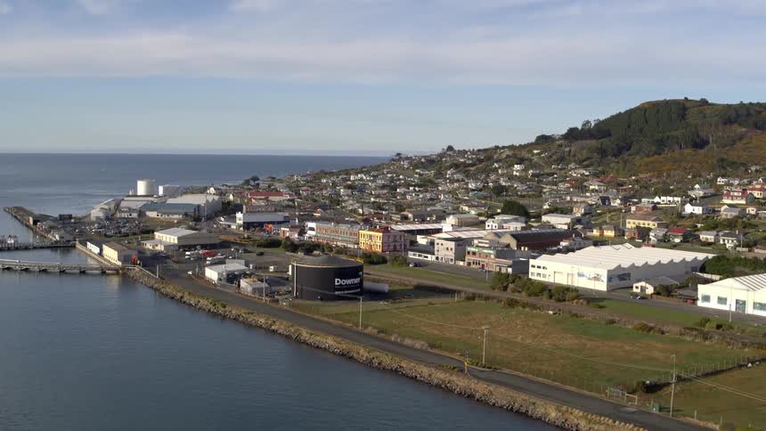 Highway paralleling the shore passes warehouses and factories on the edge of a coastal town